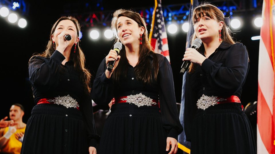 Three singers perform beneath the US flag at Battle of the Badges, Madison Square Garden