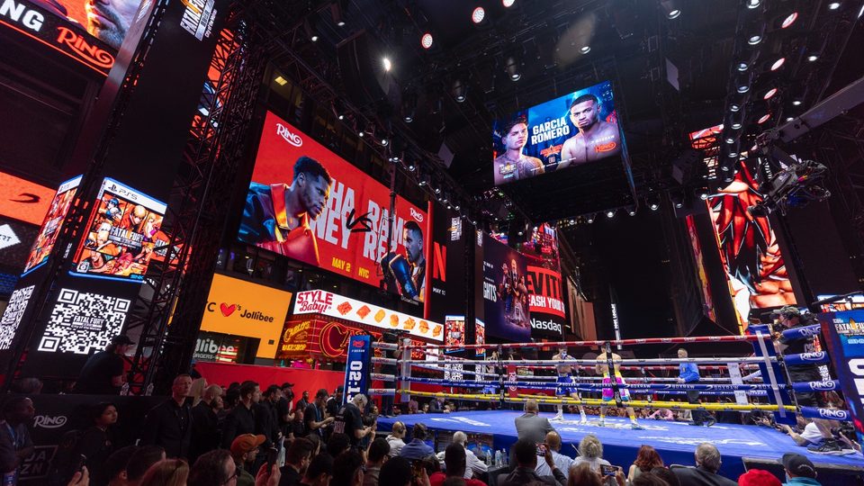 A boxing ring and screens in Times Square at night